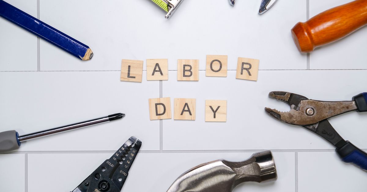 Top view of various tools with Labor Day text on white tiles, signifying the holiday and work.